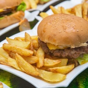 A delicious cheeseburger served with crispy fries on a white plate, perfect for fast food lovers.