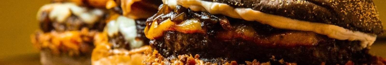 Mouthwatering close-up of gourmet burgers on a wooden board, showcasing delicious textures and toppings.